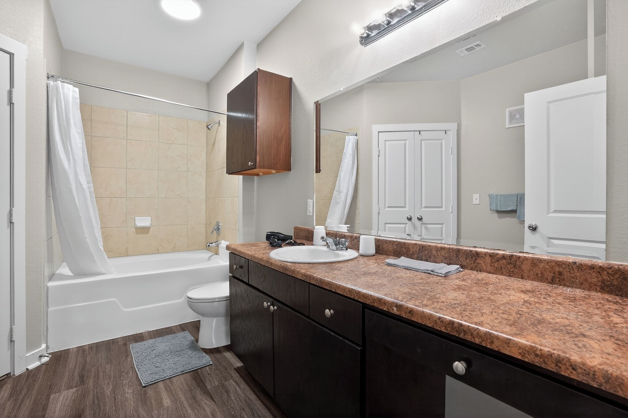 A bathroom with a bathtub, toilet, sink, and a large mirror.
