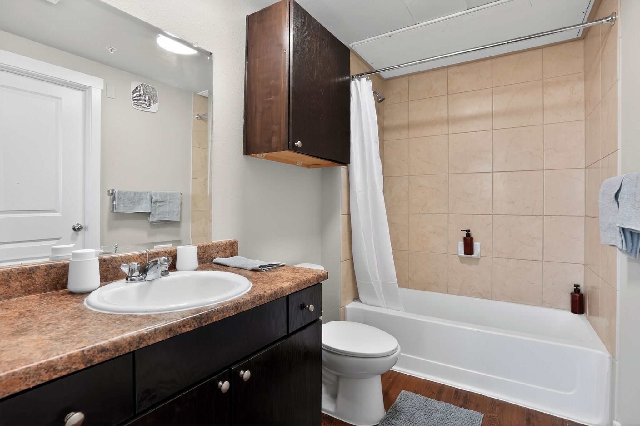 Ein Badezimmer mit Waschbecken, Spiegel, Schrank, Toilette, Badewanne und Duschvorhang.