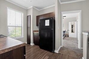 Eine Küche mit Kühlschrank, Schränken und einem Fenster.