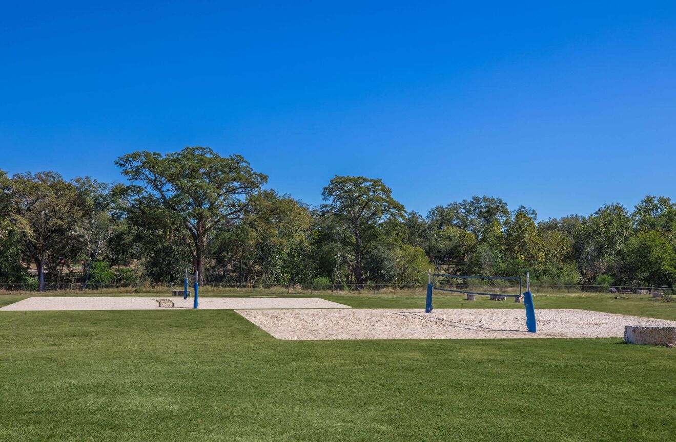 A park with open grassy areas, trees, and blue playground equipment.
