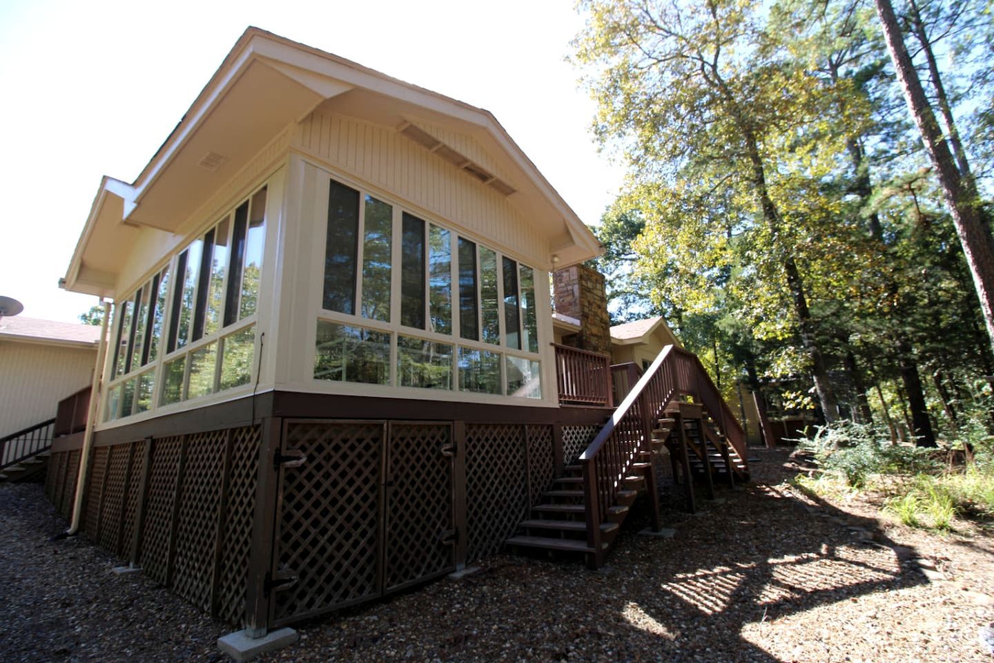 A two-story building with large windows, a wooden deck, and a staircase leading to the upper level.