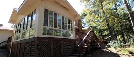 A two-story building with large windows, a wooden deck, and a staircase leading to the upper level.