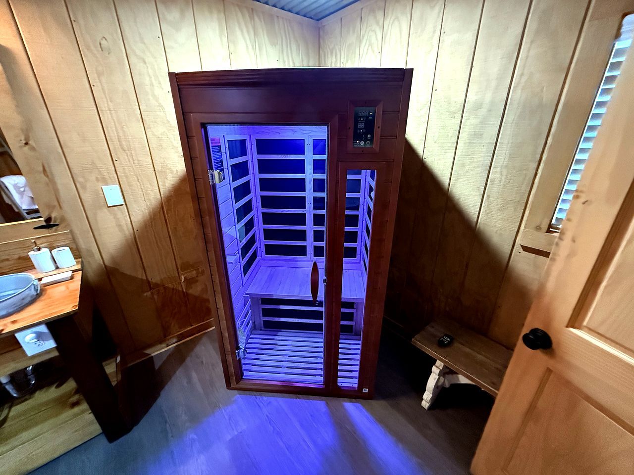 A wooden interior with a built-in sauna, a bench, and a small table with towels.