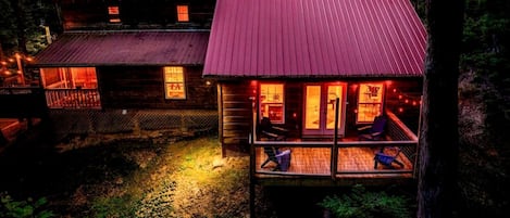 Una cabaña con porche y terraza, rodeada de árboles.