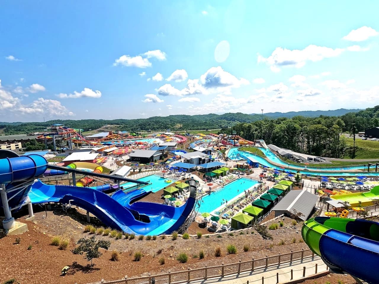 Parque acuático con varias toboganes y piscinas, rodeado de colinas.
