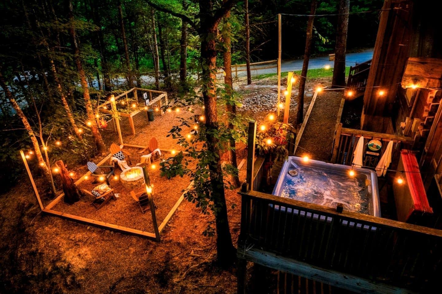A wooden deck with a hot tub, string lights, and outdoor seating.