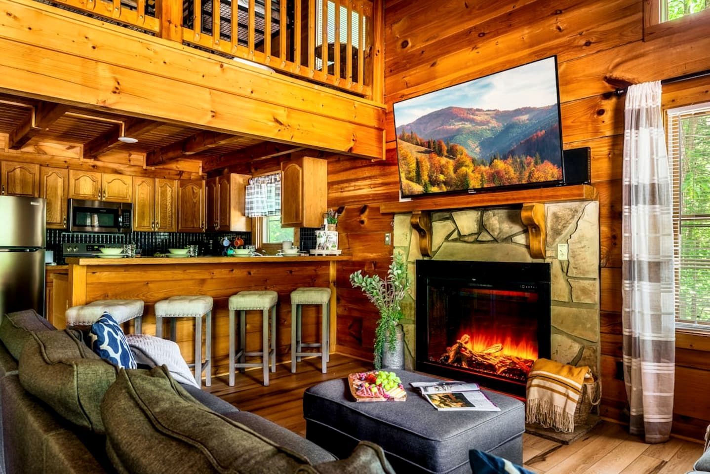 A cozy cabin interior with a fireplace, wooden bar, and a dining area.
