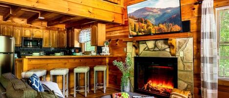A cozy cabin interior with a fireplace, wooden bar, and a dining area.