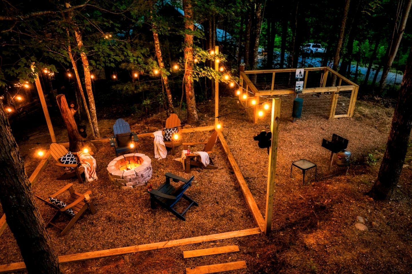 A campsite with a fire pit, seating, and string lights.