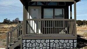 Une petite cabane à un seul étage, avec des fondations en pierre, une terrasse en bois et une porte unique portant le numéro 92.