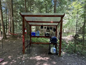 Eine rustikale Holzhütte mit Wellblechdach, umgeben von einem Wald.