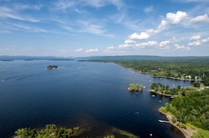 A large body of water with several small islands, surrounded by dense greenery and distant mountains.