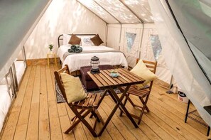 A tented accommodation with a bed, a table, and chairs. - Glamping in New York in Fully-Equipped Safari Tents Located in Broadalbin (Broadalbin)