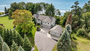 A two-story house with a driveway, garage, and a lawn with trees.