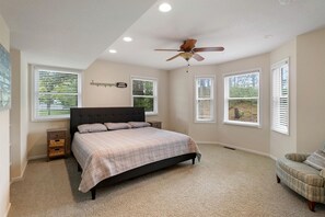 Un dormitorio con cama, ventilador de techo y ventanas con persianas.