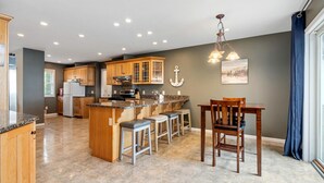 A spacious kitchen with wooden cabinets, a granite countertop, and a central island with bar stools.