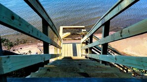 A wooden staircase leading to a beach with clear blue water.
