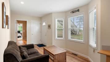 A living room with a sofa, a coffee table, and a door leading to a bedroom.