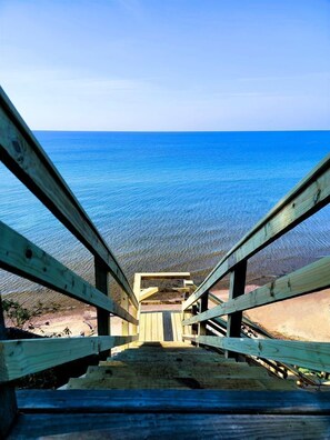 A wooden staircase leading to a beach with clear blue water.