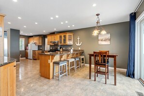A spacious kitchen with wooden cabinets, a granite countertop, and a central island with bar stools.