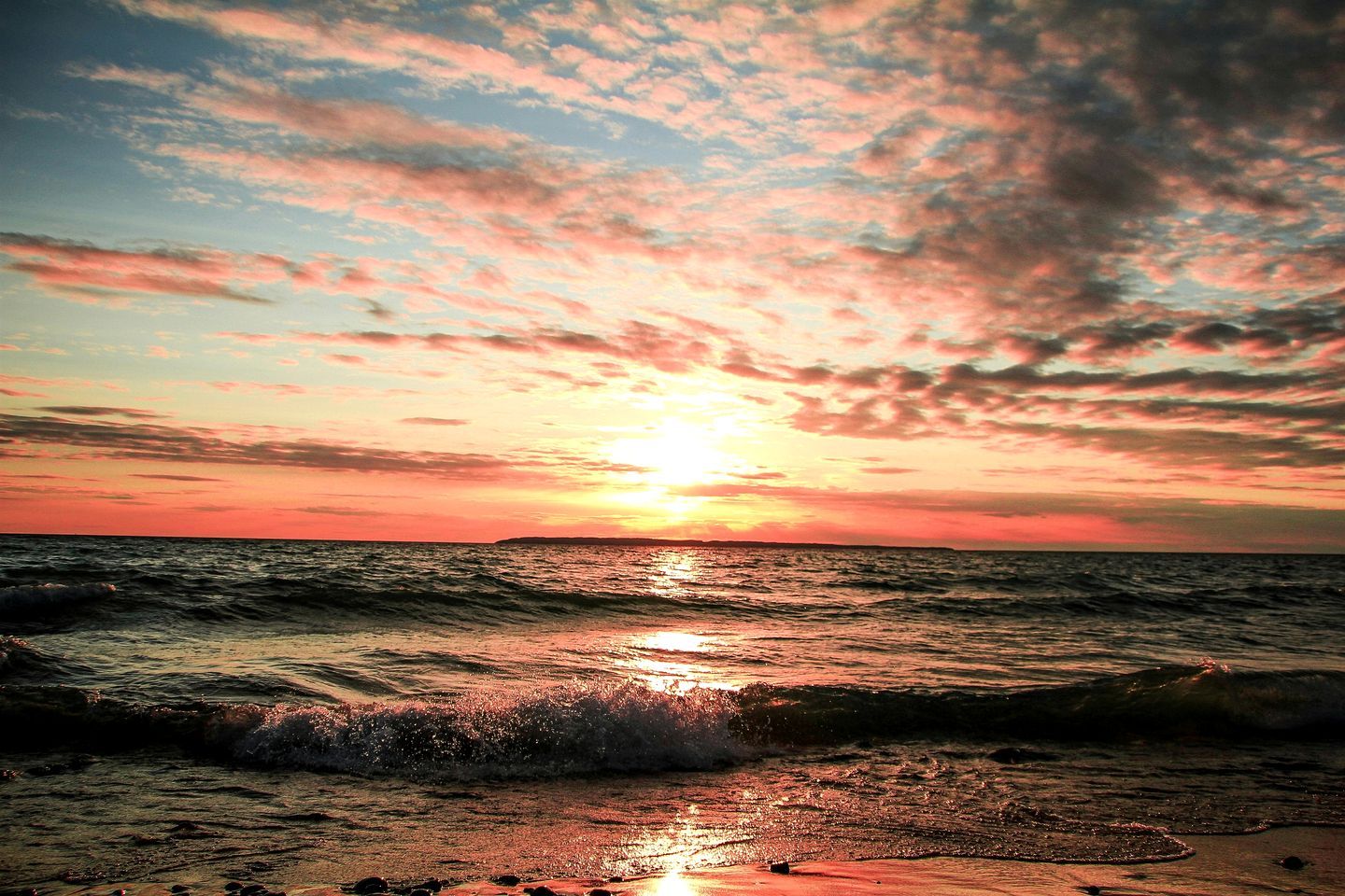 A sunset over the ocean with waves.