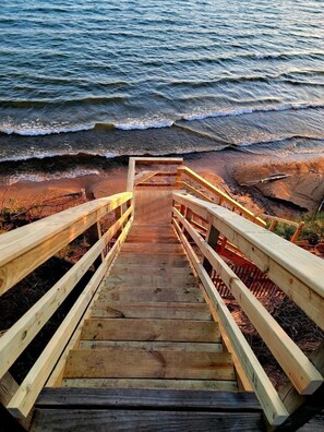 A wooden staircase leading to a beach with wooden railings.