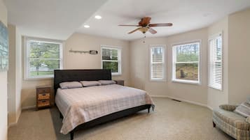 Une chambre à coucher avec un lit, un ventilateur de plafond et des fenêtres équipées de stores.