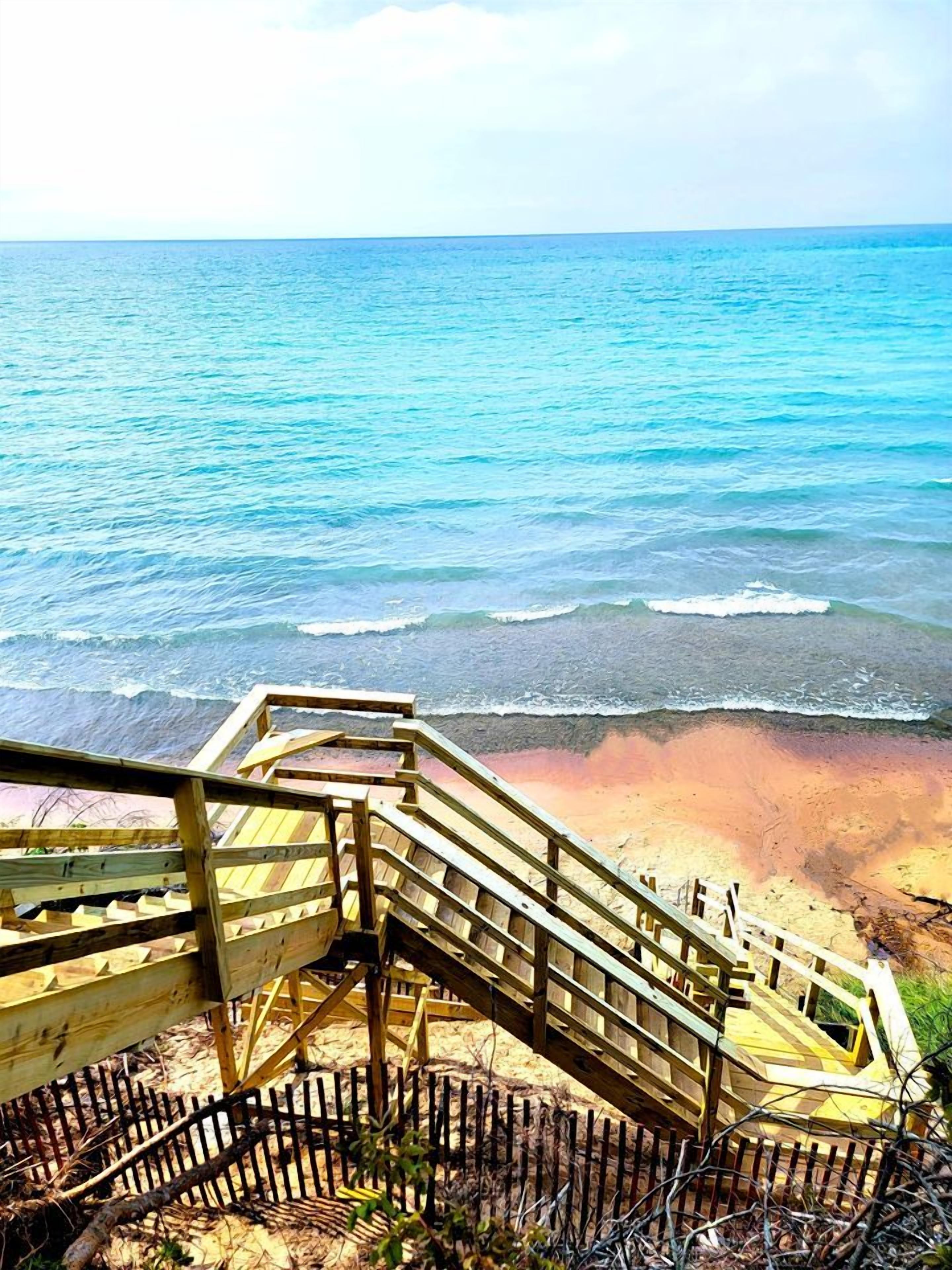 A wooden staircase leading to a beach with a view of the ocean.