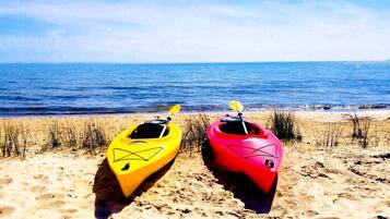 Dos kayaks en una playa arenosa con el océano al fondo.