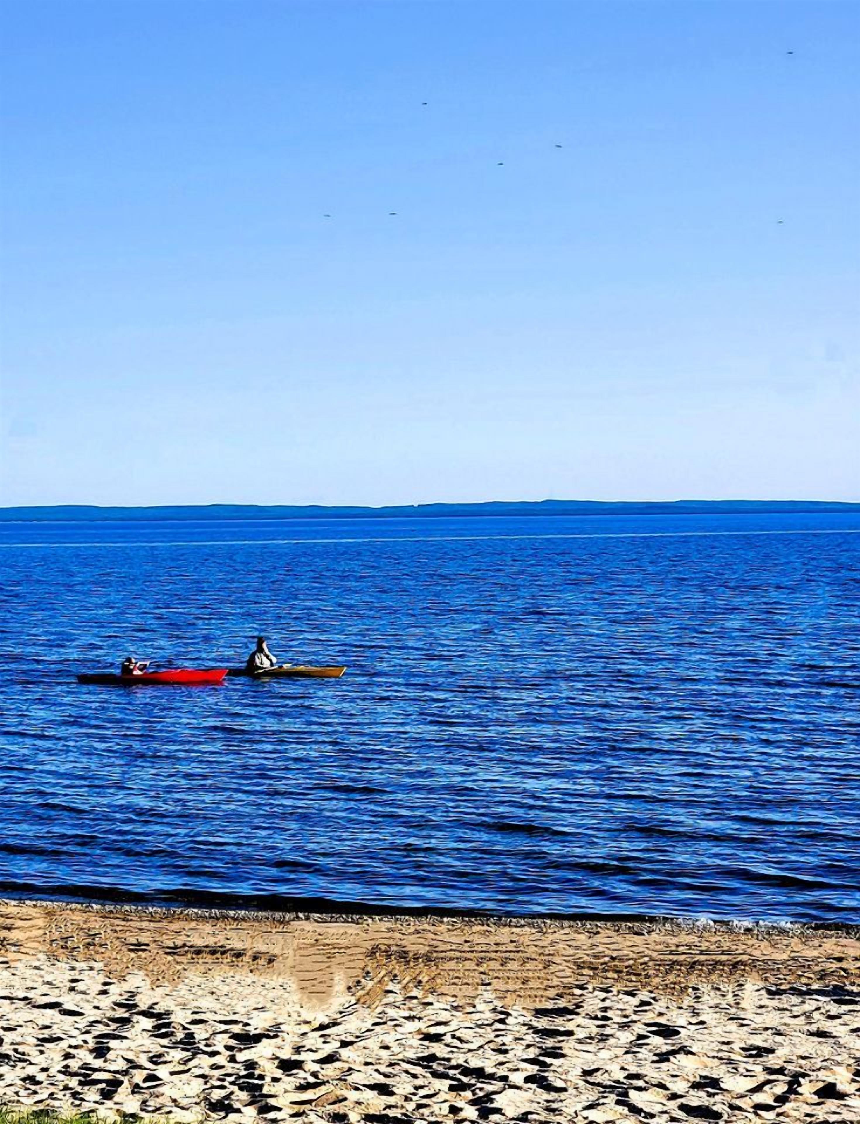 A beach with a rocky shoreline and two canoes on the water.