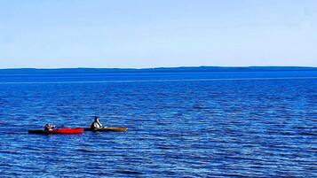 A beach with a rocky shoreline and two canoes on the water.