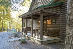 A log cabin with a porch, a sign for a restaurant, and a view of the surrounding forest.