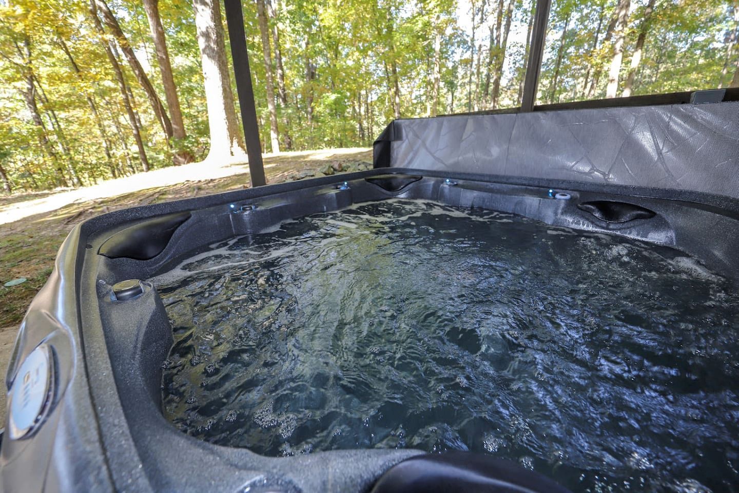 A hot tub in an outdoor setting with a forest background.