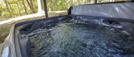 A hot tub in an outdoor setting with a forest background.