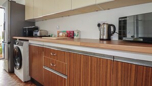 Eine kompakte Küche mit Waschmaschine, Mikrowelle, Wasserkocher und Toaster.