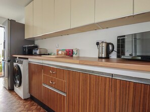 A compact kitchen with a washing machine, a microwave, a kettle, and a toaster. - 7 Chycoose Parc (Truro)