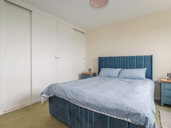 A bedroom with a bed, a nightstand, a dresser, and a wardrobe. - 7 Chycoose Parc (Truro)
