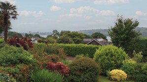 Ein Garten mit verschiedenen Pflanzen und ein Haus mit Solaranlage.