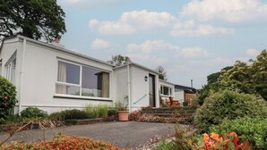 Ein weißes Wohnmobil mit einer Veranda, ein kleiner Garten mit verschiedenen Pflanzen und einem klaren Himmel.