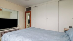 Ein Schlafzimmer mit einem Bett, einem Fernseher, einem Kleiderschrank und einem Spiegel.