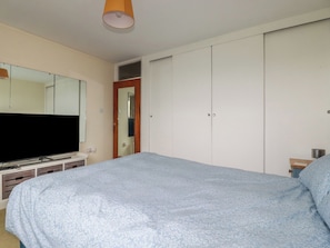 A bedroom with a bed, a television, a wardrobe, and a mirror. - 7 Chycoose Parc (Truro)