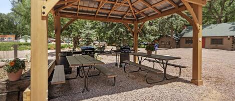 A wooden pavilion with picnic tables and barbecue grills.