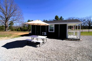 A small outdoor structure with a picnic table and umbrella, a covered seating area, and an air conditioning unit. - Charming Tiny Home Retreat Near Forest Trails & River Access in Calico Rock, Arkansas (Calico Rock)