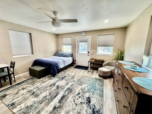 A bedroom with a bed, a desk, a chair, a dresser, a ceiling fan, and a window. - Charming Tiny Home Retreat Near Forest Trails & River Access in Calico Rock, Arkansas (Calico Rock)