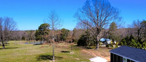 Ein Garten mit Kiesfläche, zwei blaue Adirondack-Stühle, einem kleinen Tisch und einem Schuppen.
