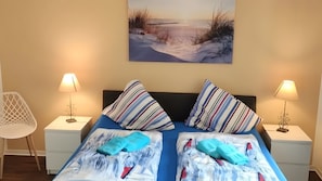 Una camera da letto con un letto, due cuscini, due comodini, due lampade e un quadro appeso al muro.