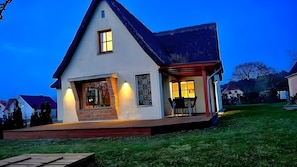 Una casa a due piani con un portico, un piccolo balcone e una finestra ben visibile.