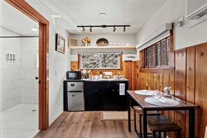 Eine kleine Küche mit einer Mikrowelle, einem Kühlschrank und Holzschränken.