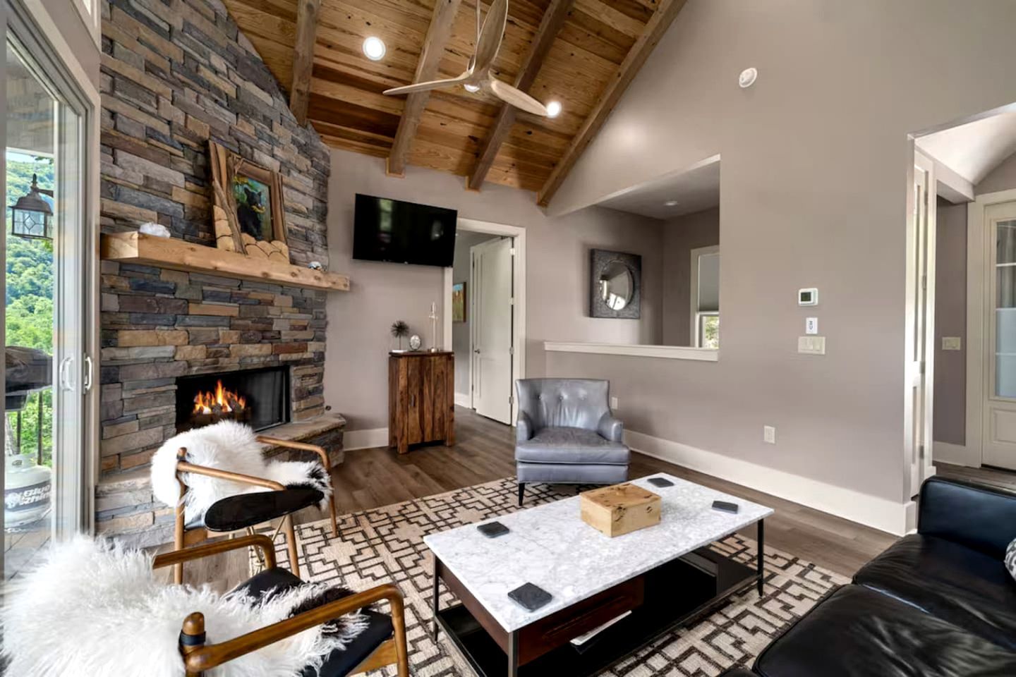 A living room with a stone fireplace, leather furniture, a marble coffee table, and a large mirror.