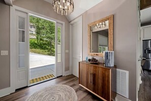 A modern interior with a wooden cabinet, a large mirror, and a view of the outdoors.